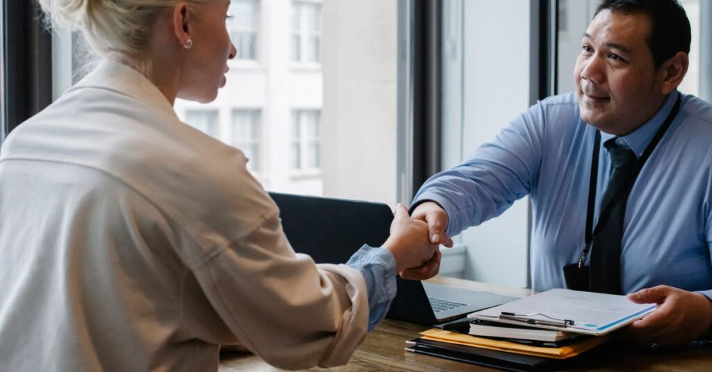 Ethnic male entrepreneur shaking hand of female candidate during job interview in business company