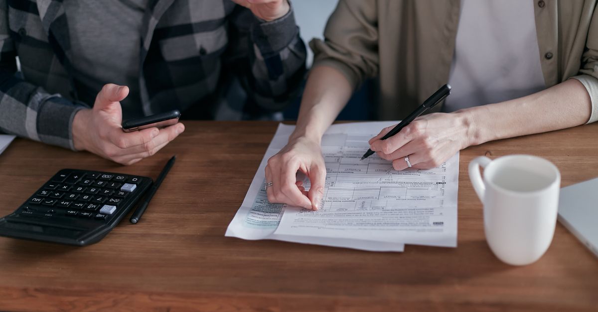 A couple collaboratively managing finances with papers and calculator in hand.