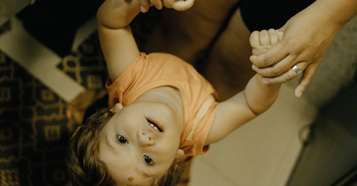 A happy child holds hands with a parent indoors, expressing excitement and connection.