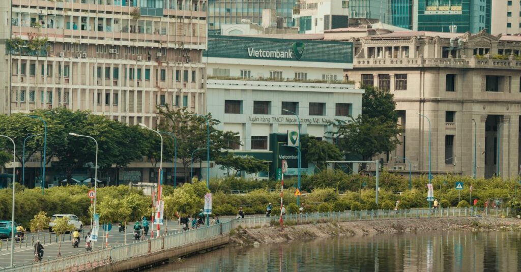 Street scene featuring Vietcombank building along a riverside in urban Ho Chi Minh City, Vietnam.