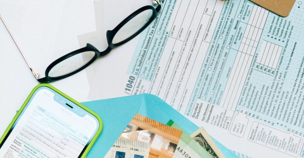 Close-up of tax forms, smartphone, and dollar bills for financial analysis and preparation.