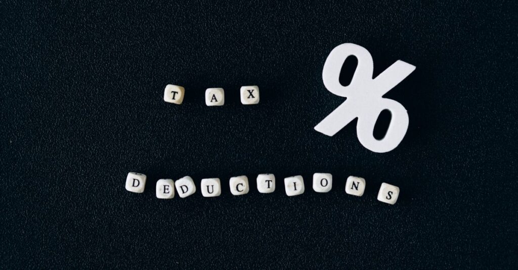 Conceptual image of tax deductions with alphabet blocks and percent symbol on black surface.