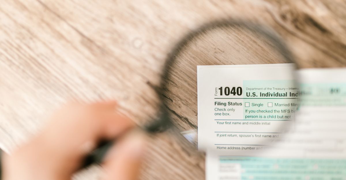 Close-up image of IRS Form 1040 under a magnifying glass on a wooden surface.