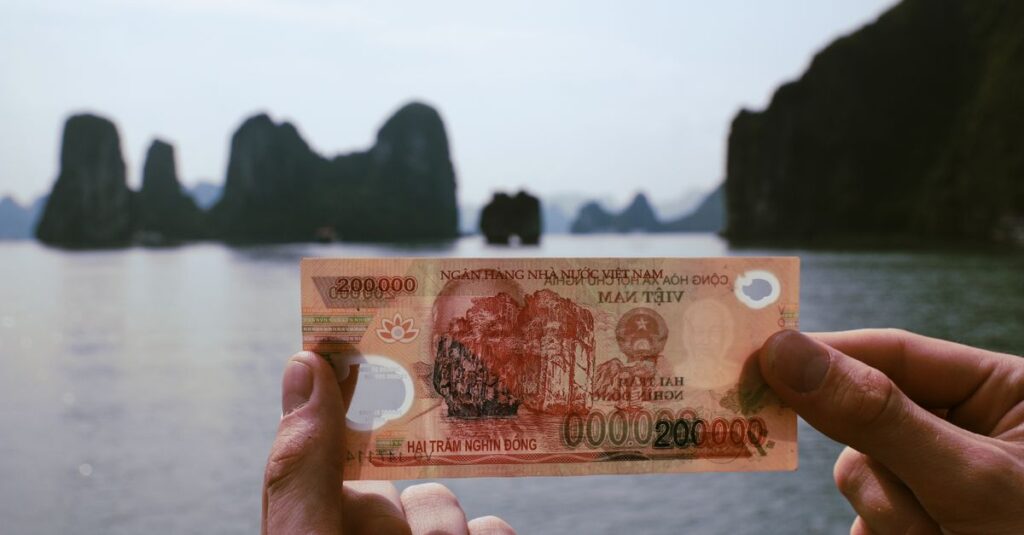 Hands holding Vietnamese Dong with Halong Bay in the background, a fusion of finance and travel.