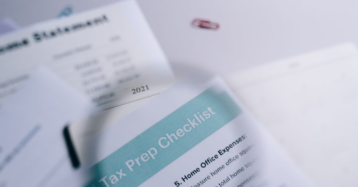 Close-up of tax preparation checklist and income statement with paperclips.
