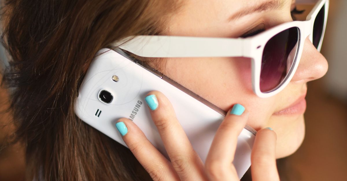 Close-up of a woman talking on a smartphone while wearing white sunglasses.