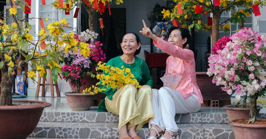 Two women enjoying the Tet Festival with blossoming flowers and traditional decor in Vietnam.