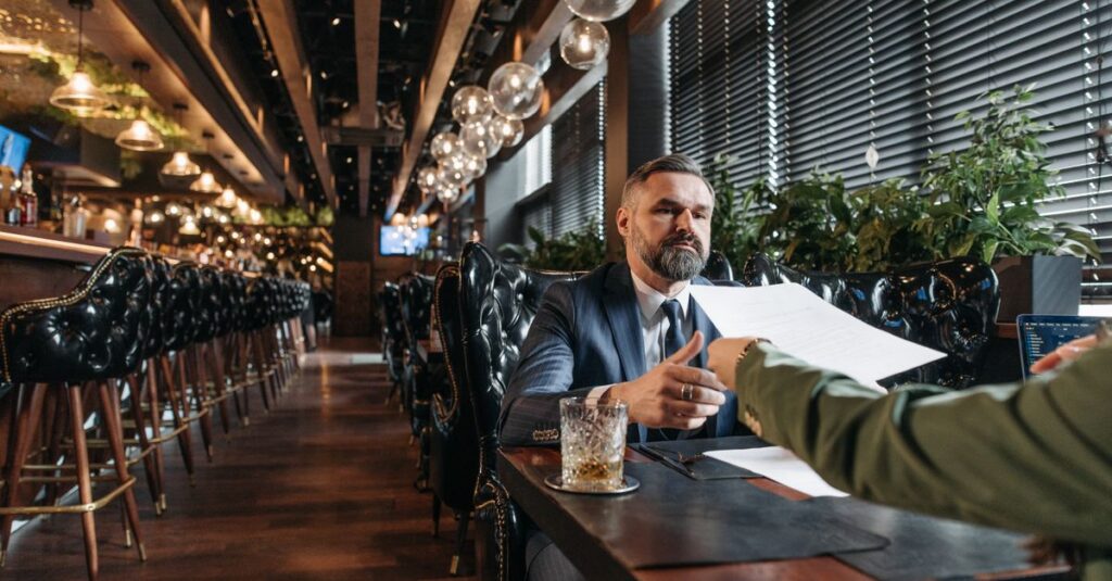 Businessman reviewing contract during a meeting in a stylish restaurant setting.