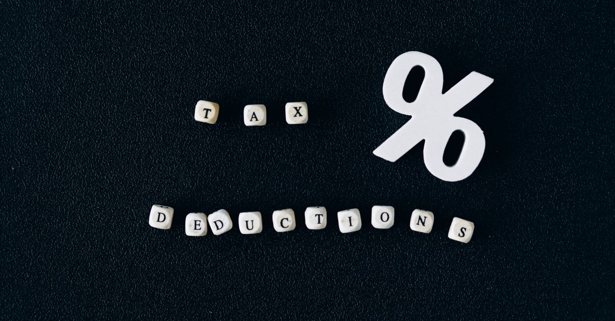 Conceptual image of tax deductions with alphabet blocks and percent symbol on black surface.