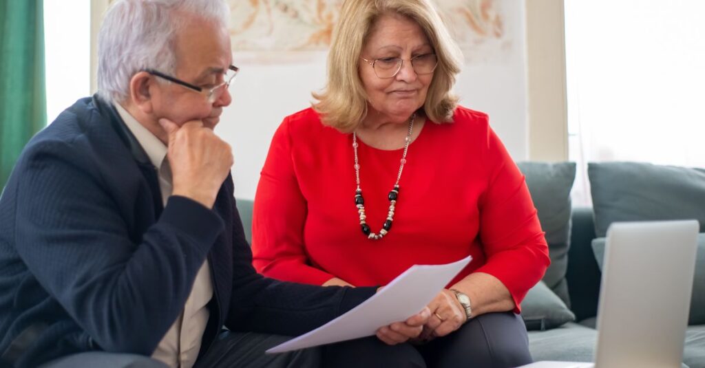 Elderly couple reviewing financial documents together at home in Portugal.