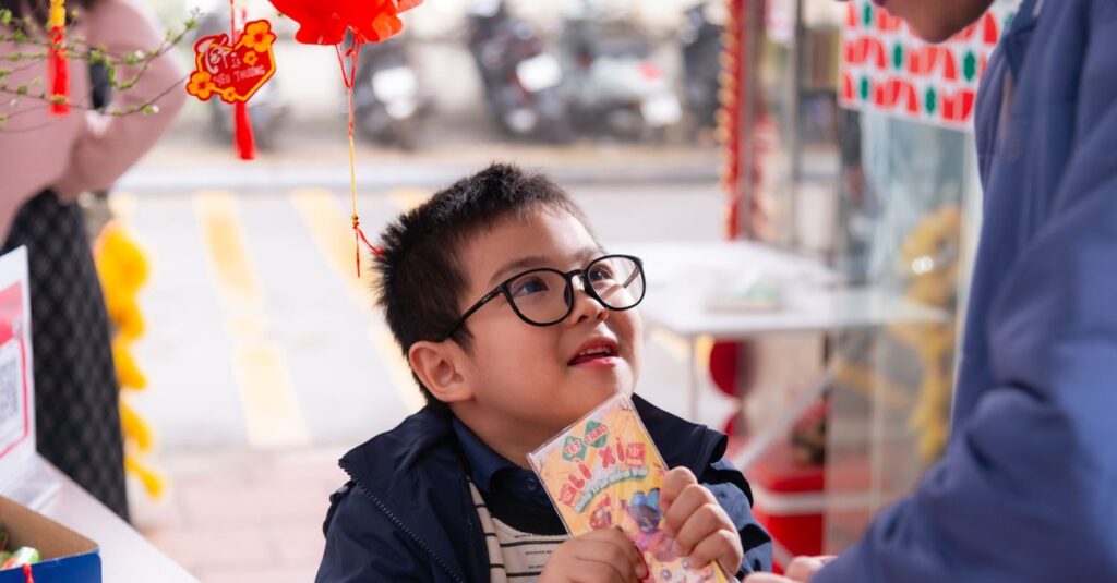 Young boy joyfully receives lucky money envelope during Lunar New Year celebration outdoors.
