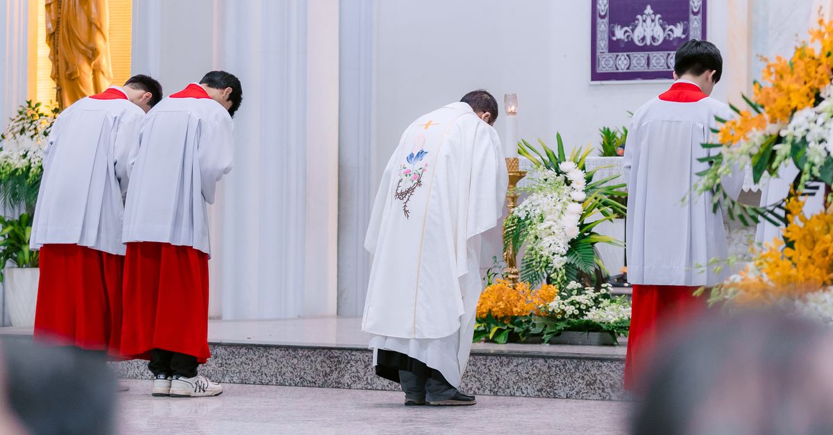 Priests in ceremonial attire bowing during a religious service inside a church.